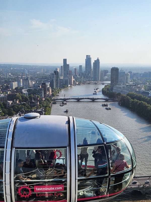 Inside a capsule of the London Eye, tourists on a sunny day enjoy the panoramic view overlooking the Thames River. Part of a London Christian Tour, the skyline boasts modern skyscrapers while boats glide below, enriching this unique exploration of London’s vibrant tapestry.